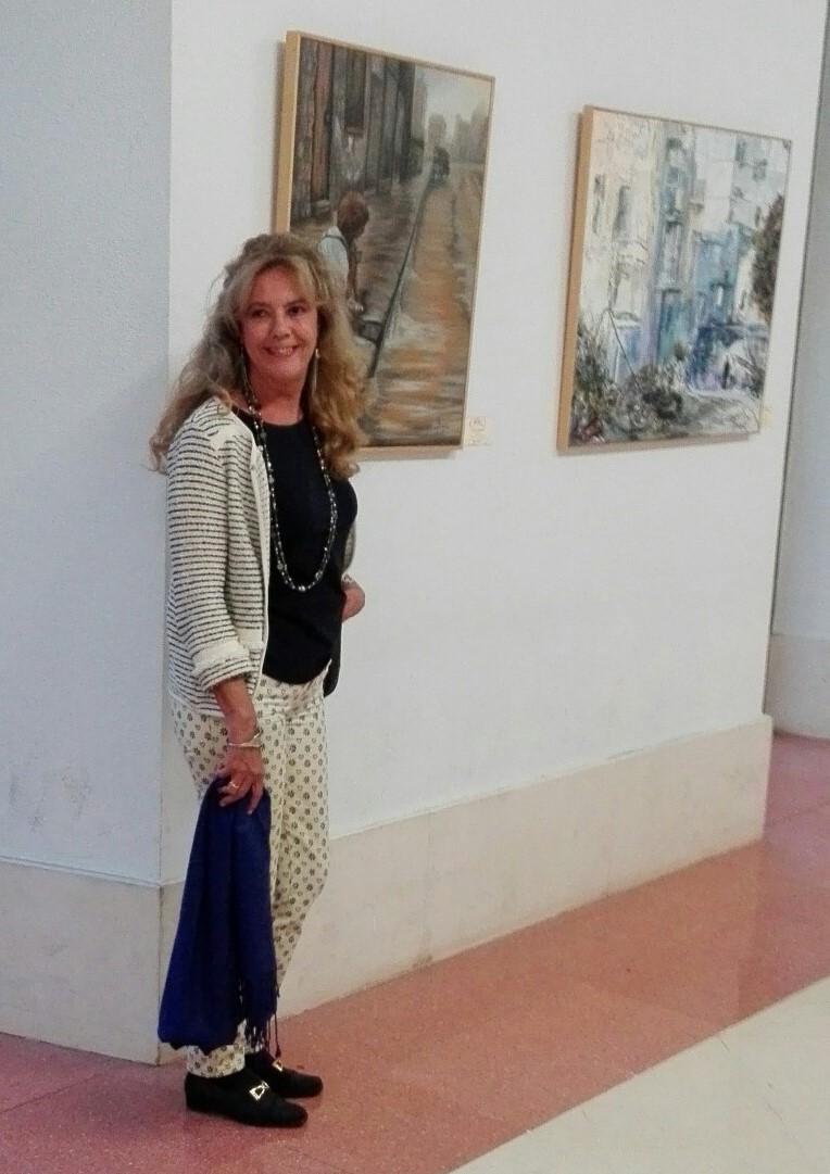 Mujer posando junto a dos cuadros en un pasillo de la sala.